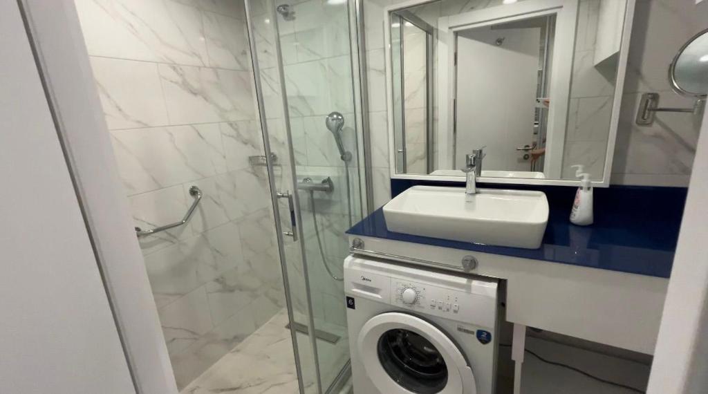 a bathroom with a washing machine and a sink at Orbi City D2 in Batumi