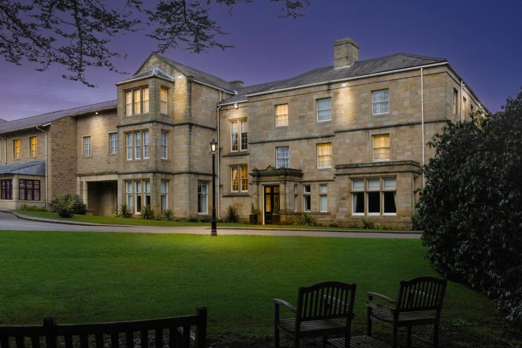 a large building with two benches in front of it at Weetwood Hall Estate in Leeds