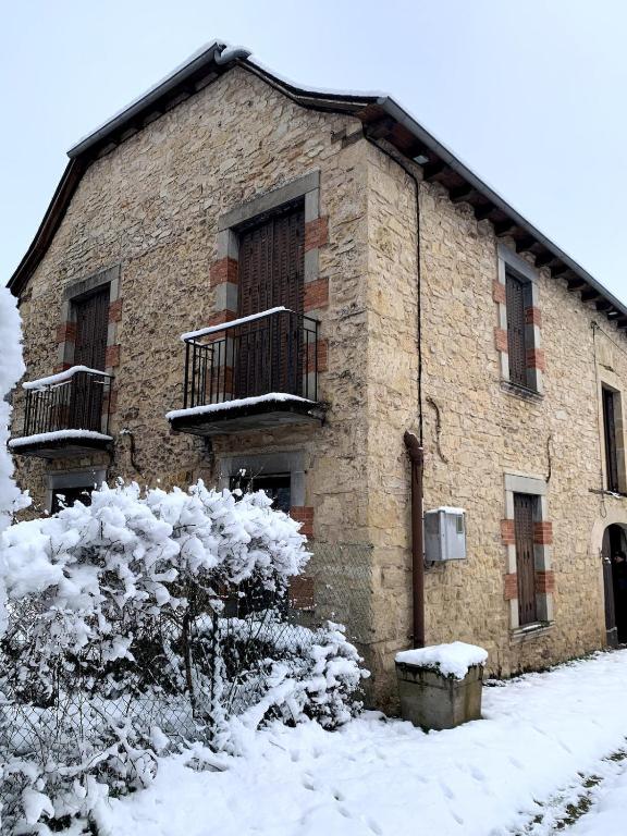 a brick building in the snow with a balcony at souvenirs rignacois in Rignac