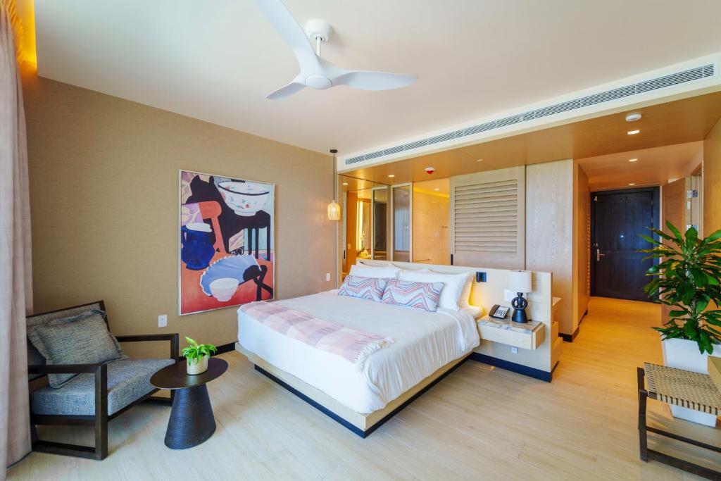 a bedroom with a large bed and a chair at Wyndham Grand Barbados Sam Lords Castle All Inclusive Resort in Saint Philip