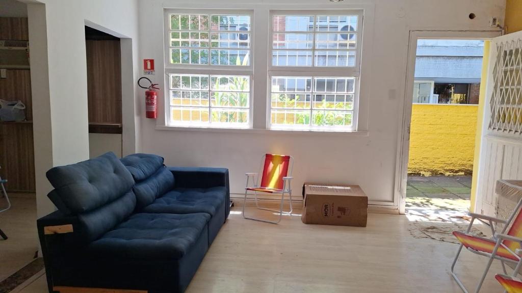 a living room with a blue couch and two windows at Up Hostel in Porto Alegre