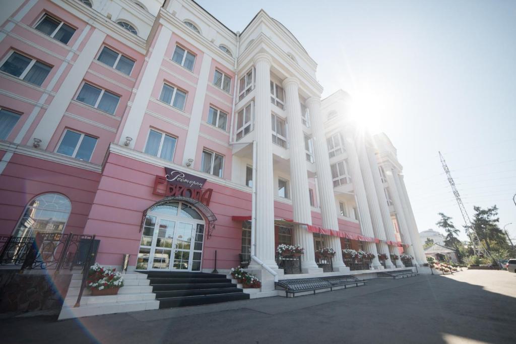 un bâtiment rose et blanc dans une rue dans l'établissement Europa Hotel, à Irkoutsk