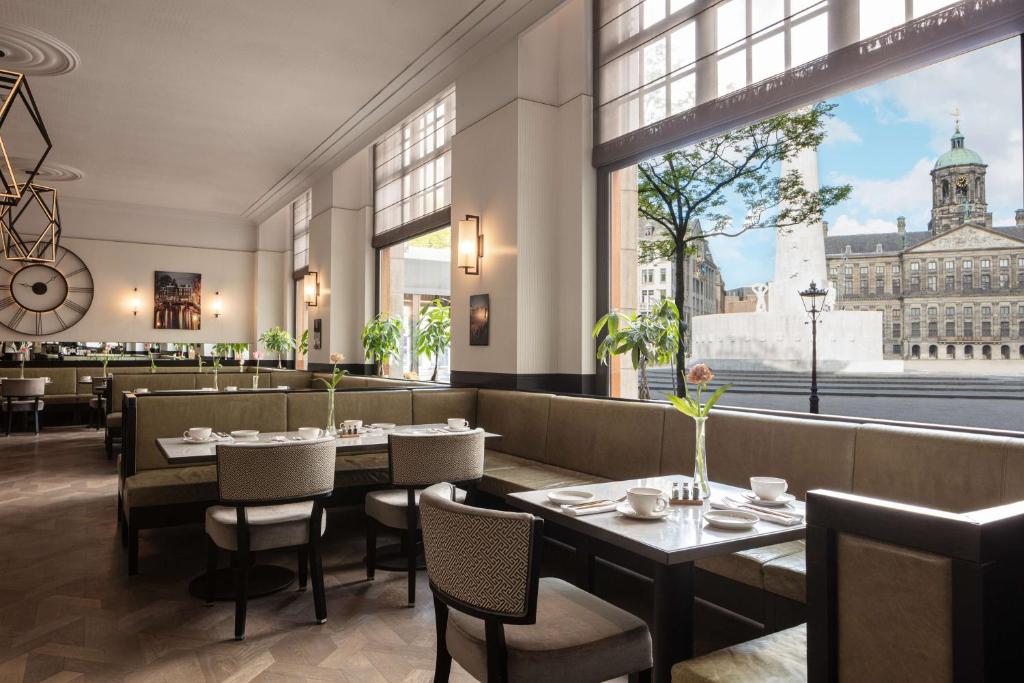 a restaurant with tables and chairs and a view of the city at Anantara Grand Hotel Krasnapolsky Amsterdam in Amsterdam