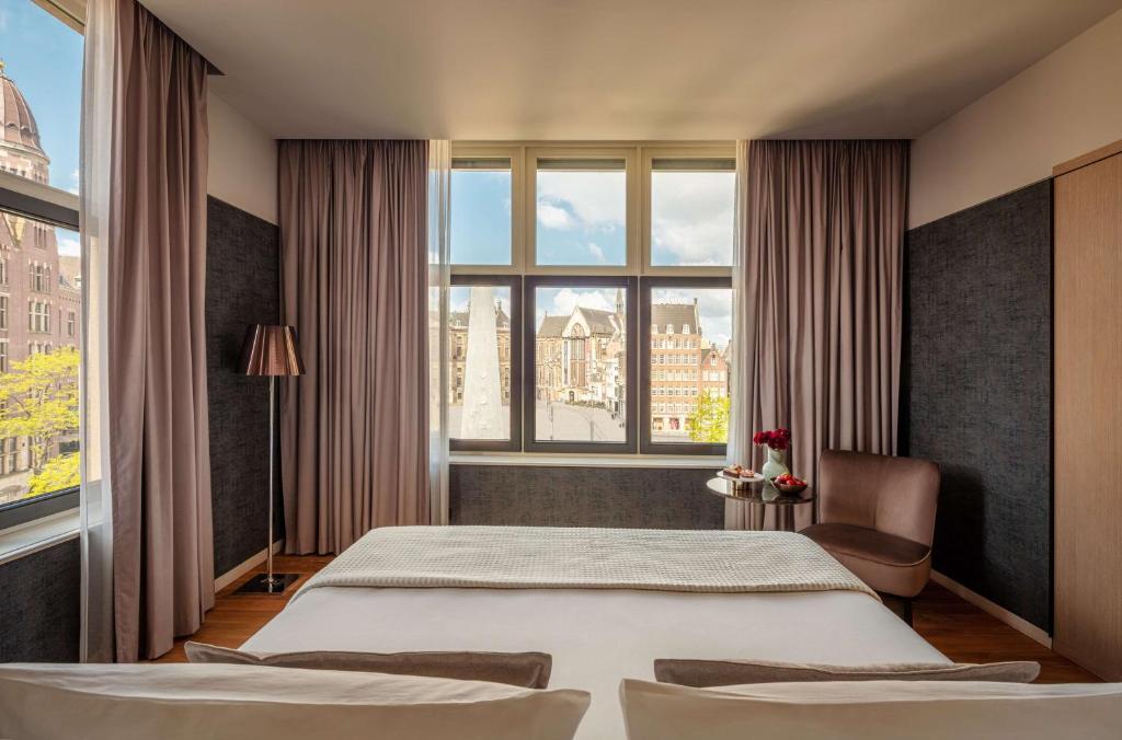 a bedroom with a large bed and a large window at Anantara Grand Hotel Krasnapolsky Amsterdam in Amsterdam