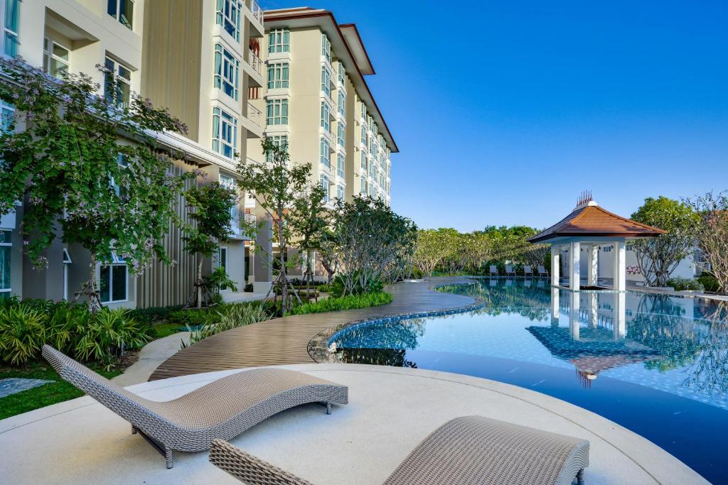 una piscina con sedie e un gazebo accanto a un edificio di Harmony Resort Hotel a Chiang Mai