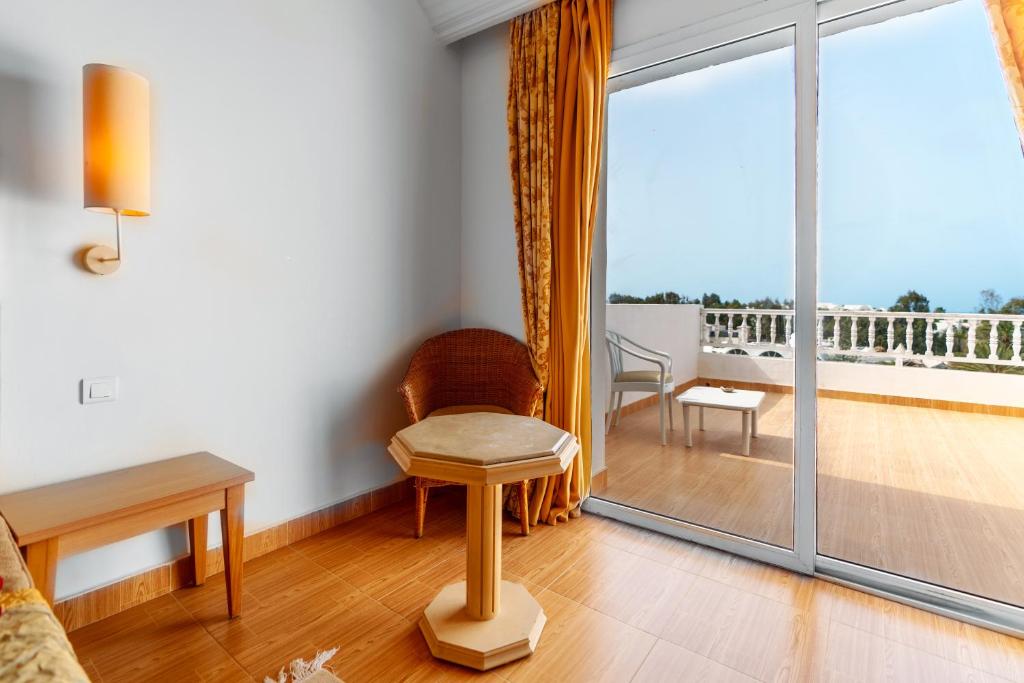 a living room with a chair and a large window at Iris Hotel & Thalasso in Taguermess