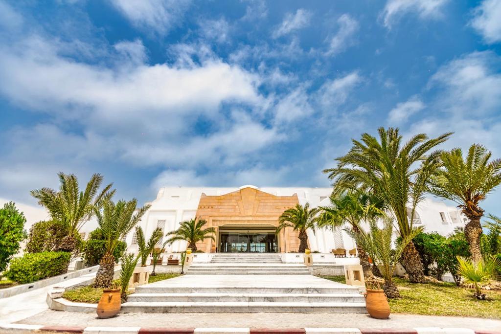 a building with palm trees in front of it at Iris Hotel & Thalasso in Taguermess