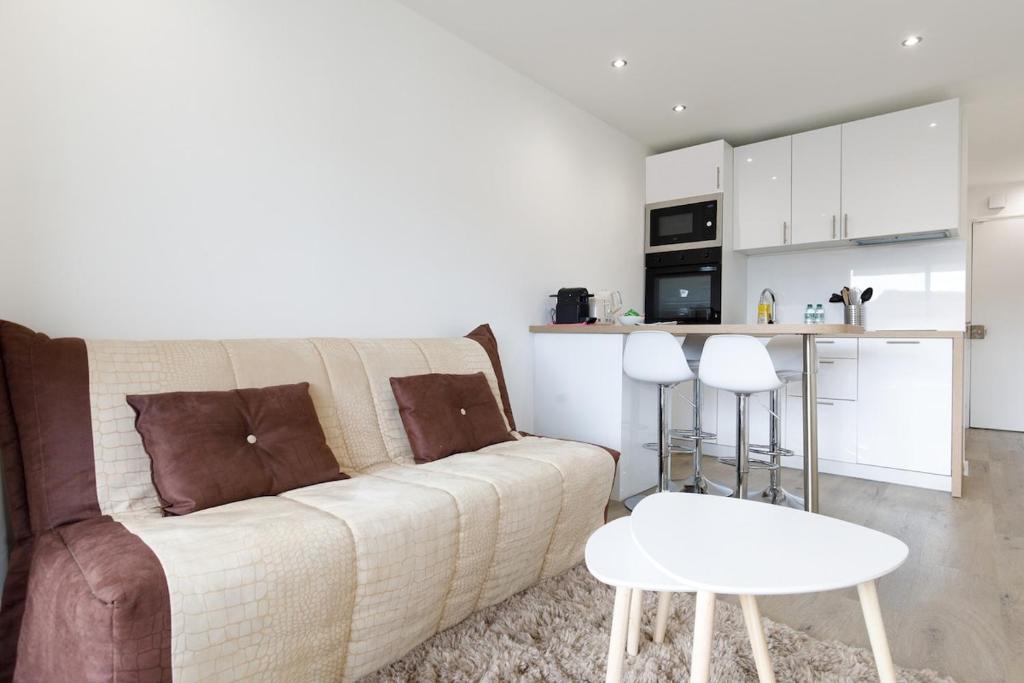 un salon avec un canapé et une cuisine dans l'établissement Le Chataigner - Center - Parking - Clim - Wifi, à Cannes