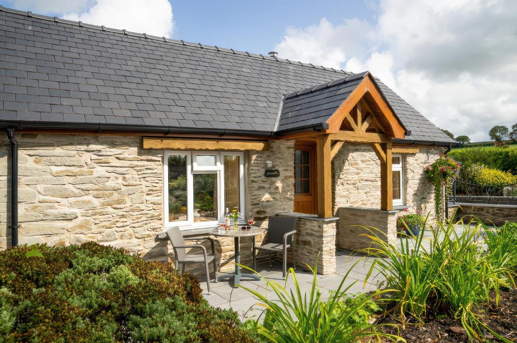 Ce cottage en pierre dispose d'une terrasse avec une table et des chaises. dans l'établissement Gwaun Cottage, à Cardigan