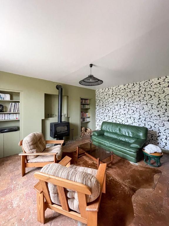 - un salon avec un canapé vert et une cheminée dans l'établissement Le Presbytère, maison de campagne familiale, à La Poterie-au-Perche