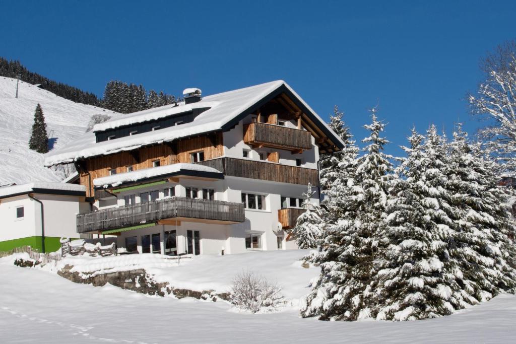a building in the snow with trees in front at Das Kleemanns in Mittelberg
