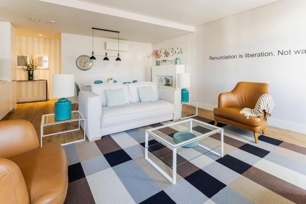 a living room with a white couch and a chair at Chiado Square Apartments | Lisbon Best Apartments in Lisbon
