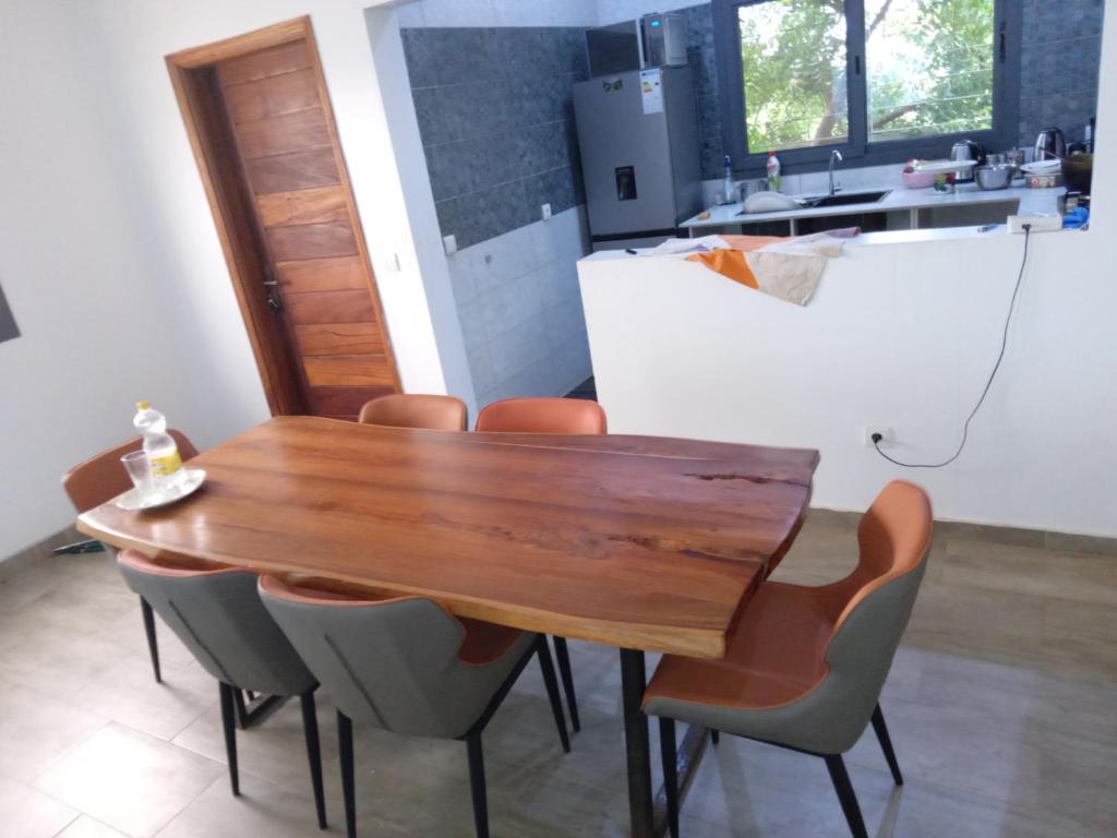 una mesa de madera y sillas en la cocina en Villa 2 chambres salon piscine saly, en Mbour