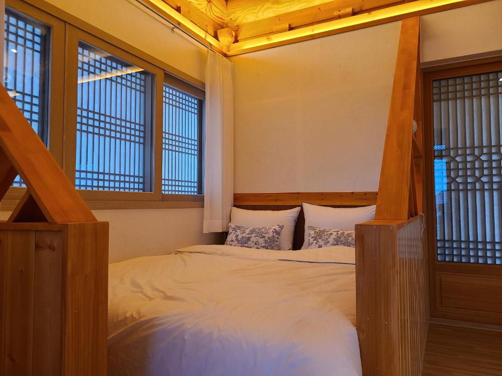 ein Schlafzimmer mit einem Bett und zwei Fenstern in der Unterkunft Hanok stay Mokhyang in Gyeongju