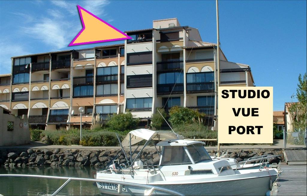 un bateau dans l'eau devant un bâtiment dans l'établissement Cap d'Agde Naturiste côté PORT, au Cap d'Agde