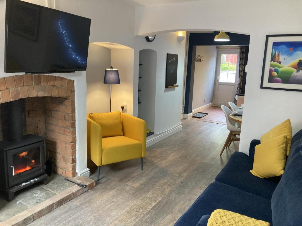 a living room with a couch and a fireplace at Witcroft Cottage in Pershore
