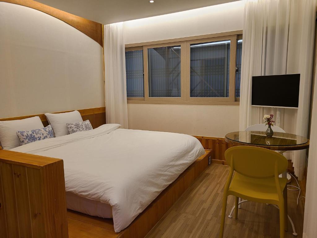 ein Schlafzimmer mit einem Bett und einem Tisch und einem Fernseher in der Unterkunft Hanok stay Mokhyang in Gyeongju