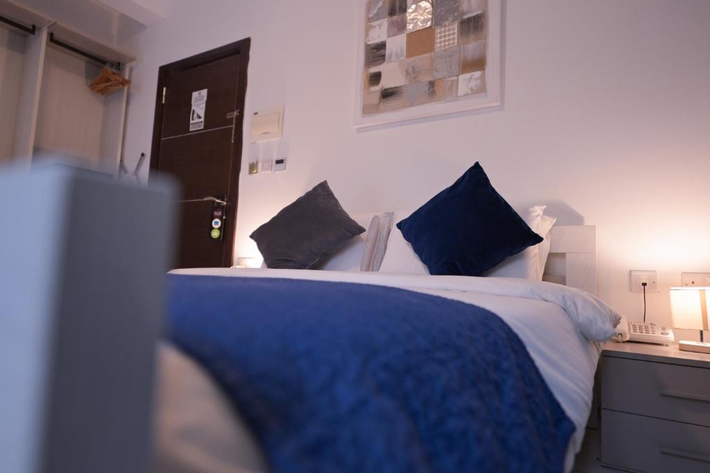 a bedroom with a bed with blue pillows and a desk at The Exiles Hotel in Sliema