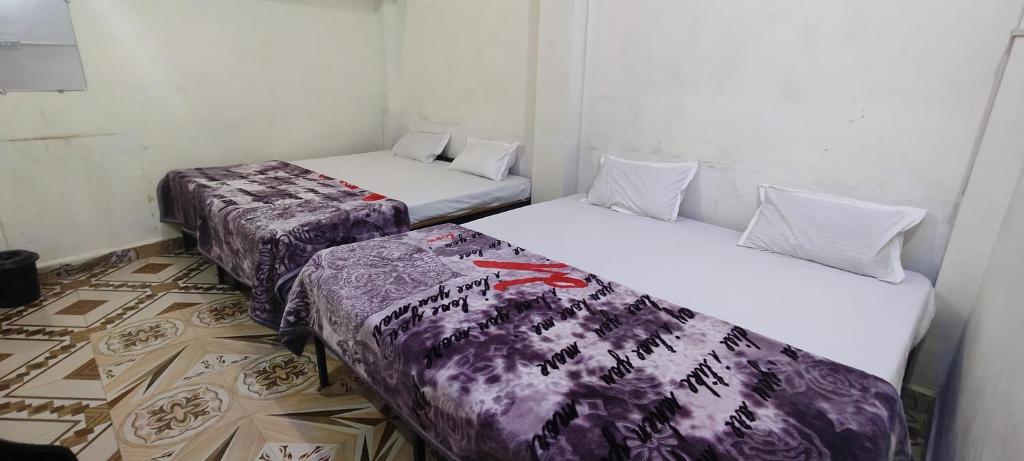 three beds in a room with purple and white sheets at SATYAMOHAN GUEST House in Ujjain