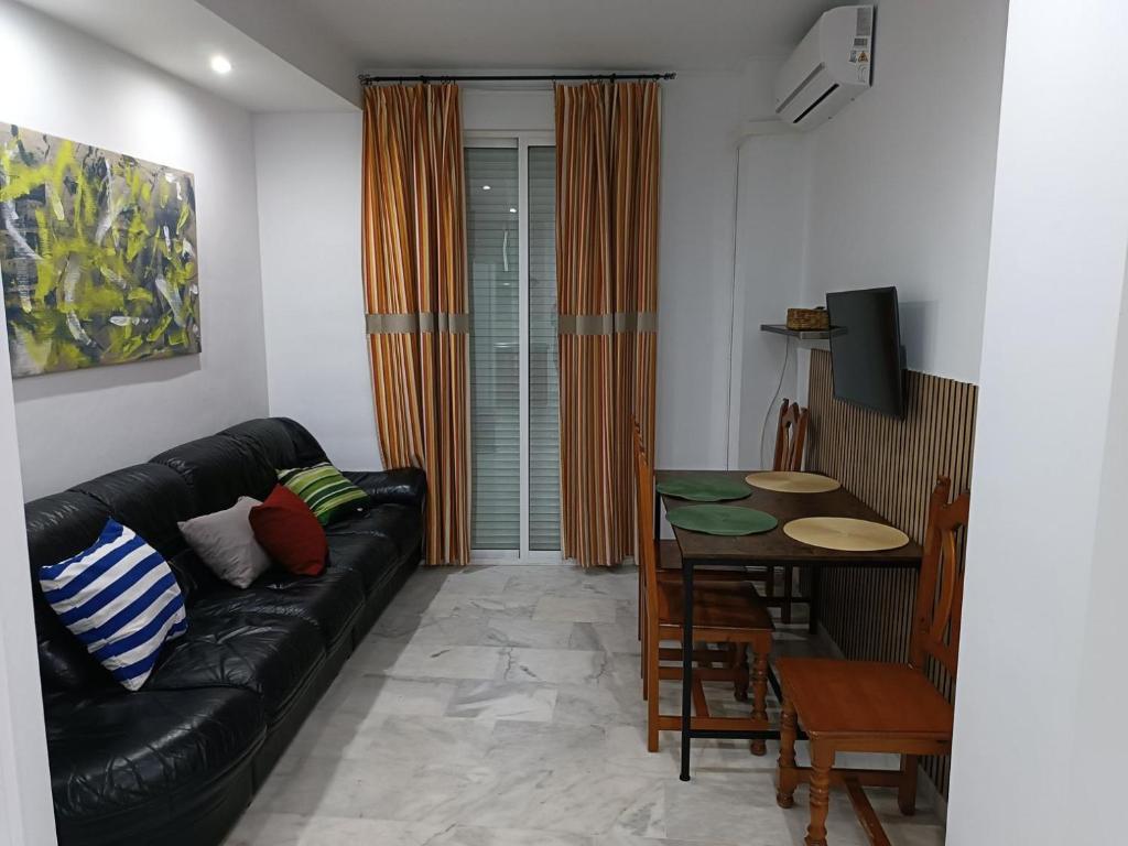 Una sala de estar con un sofá de cuero negro y una mesa. en Apartamento Al Sur del Sur, en Sanlúcar de Barrameda
