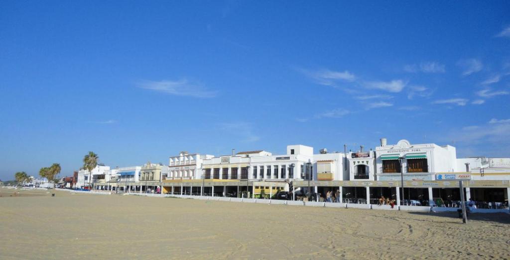 una fila de edificios blancos en una playa en Apartamento Al Sur del Sur, en Sanlúcar de Barrameda