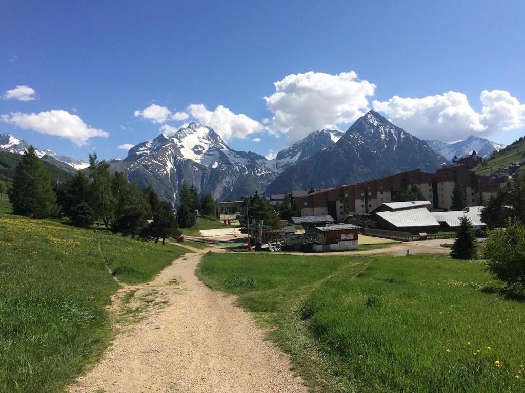un chemin de terre dans un champ avec des montagnes en arrière-plan dans l'établissement Les 2 Alpes Apartment 6 pers Plein Sud, apartment & parking, à Les Deux Alpes