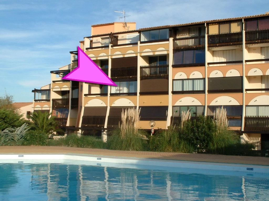 un triangle rose est assis devant un bâtiment dans l'établissement Cap d'Agde Naturiste côté Piscine, au Cap d'Agde