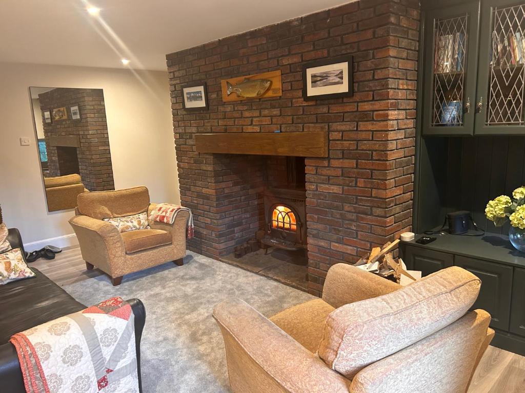 a living room with a brick fireplace and two chairs at Aldernaig Mill in Invergarry