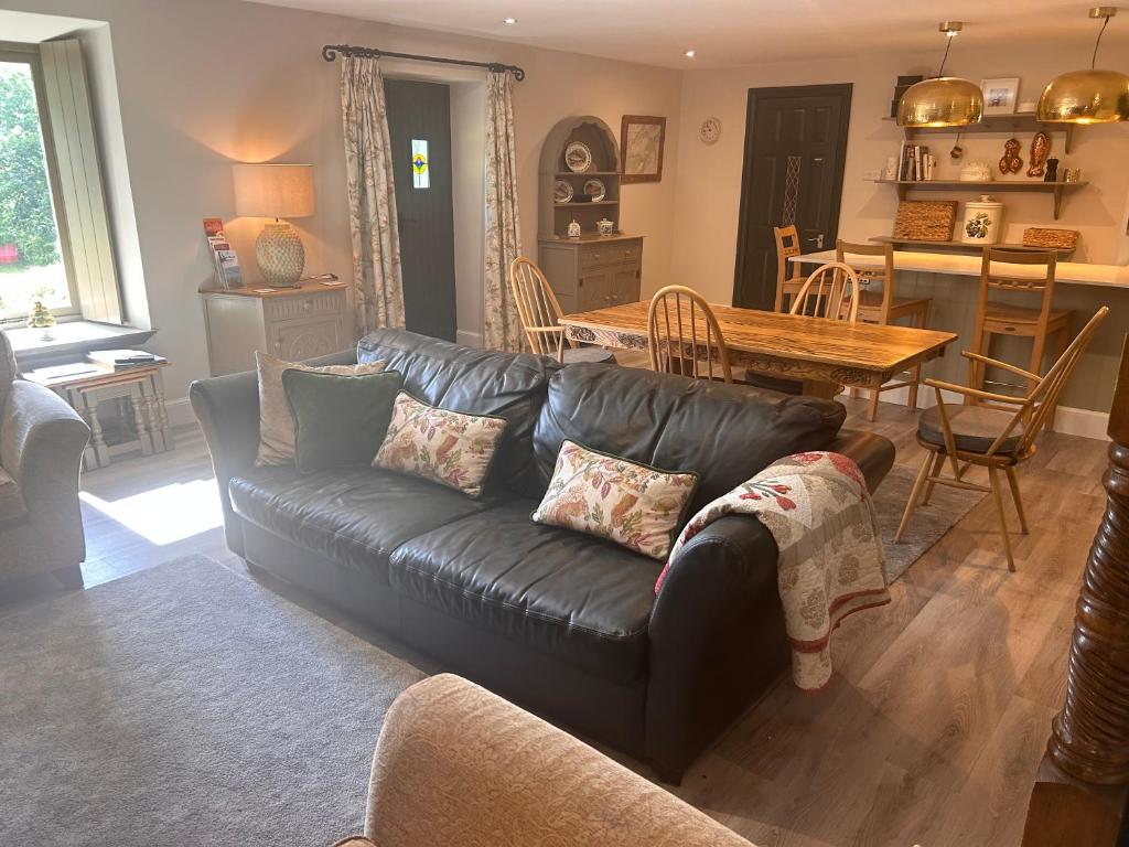 a living room with a black leather couch and a table at Aldernaig Mill in Invergarry