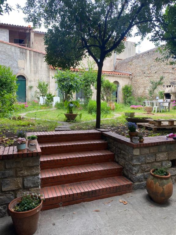 un escalier avec un arbre dans une cour dans l'établissement Appartement cosy avec oasis privée, salle de jeux, vélos bienvenus, à Carcassonne