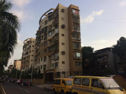 a yellow van parked in front of a tall building at Cozy Vibes in Navi Mumbai