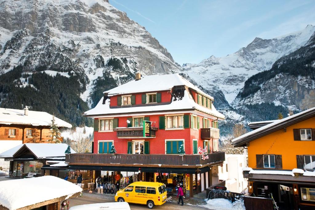 a yellow van parked in front of a building with a mountain at Bernerhof Residence in Grindelwald