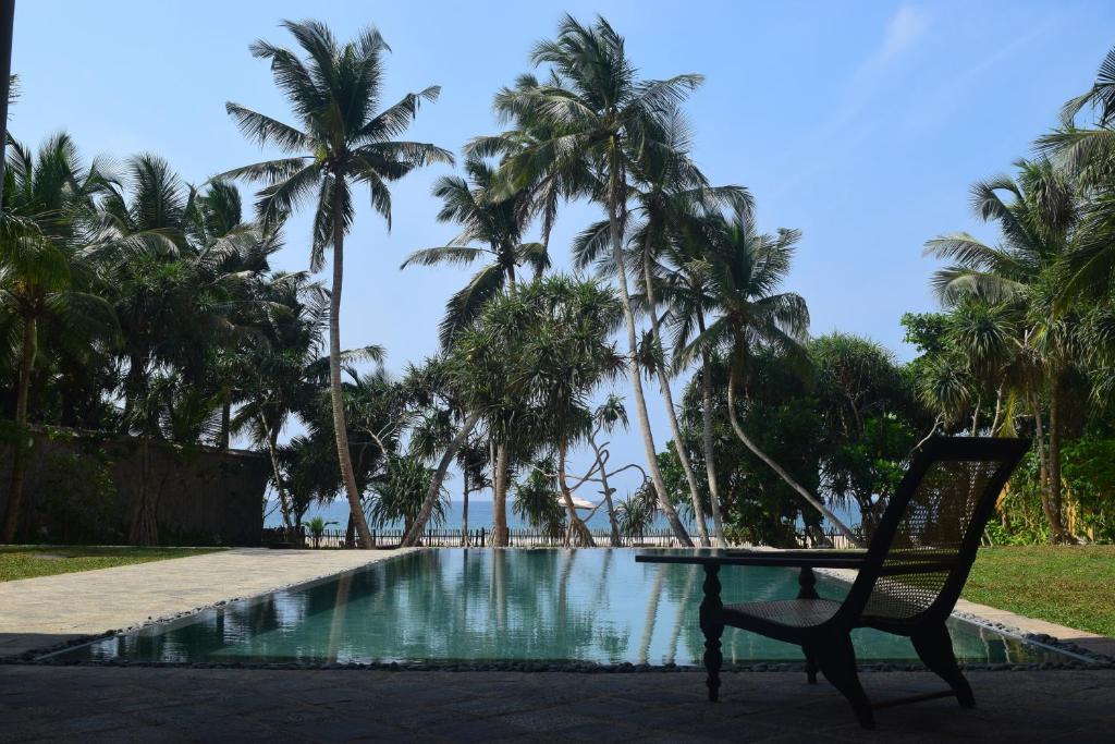 a park bench in front of a large body of water at Villa Saffron Hikkaduwa in Hikkaduwa