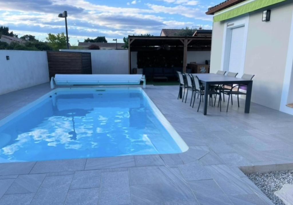 - une piscine sur une terrasse avec une table et des chaises dans l'établissement Maison vacances, à Gallargues-le-Montueux