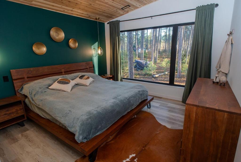una camera da letto con un letto e una grande finestra di Brand New Black Fox Cabin with Private Nordic Spa a Sprucedale