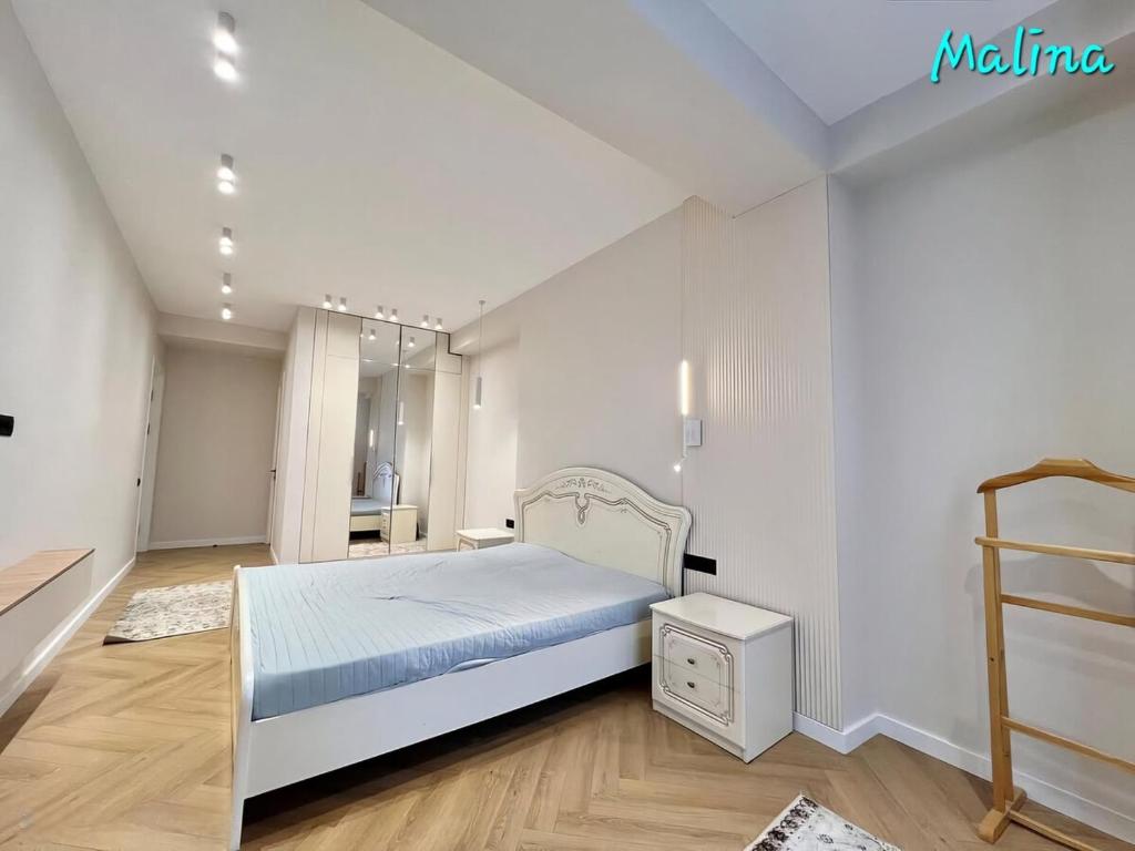 a bedroom with a white bed and a wooden floor at 3 Bedroom Apartment Malina Residence in Bishkek