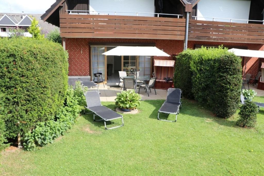 a yard with two chairs and an umbrella at Appartement 5 in Scharbeutz