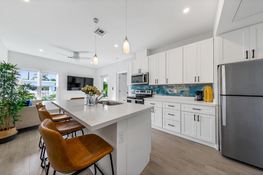 a kitchen with white cabinets and a kitchen island with chairs at Affordable Luxury Apartments, 3 Min to Beach in West Bay