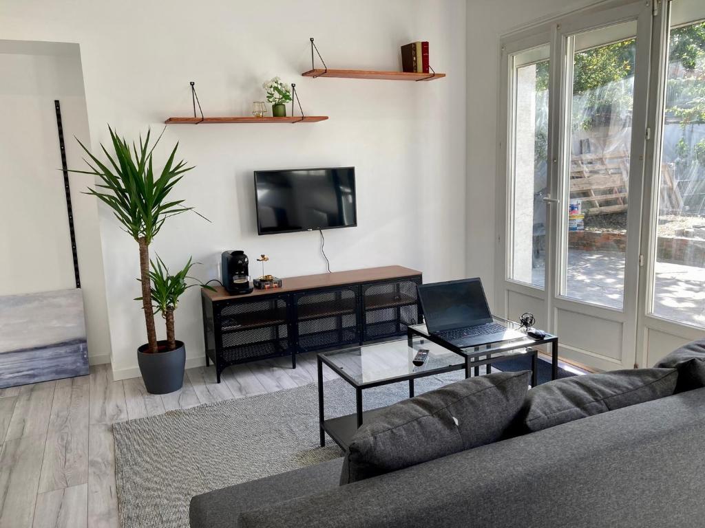 un salon avec un canapé et un ordinateur portable sur une table dans l'établissement Studio lumineux Gagny - 2min du RER, à Gagny