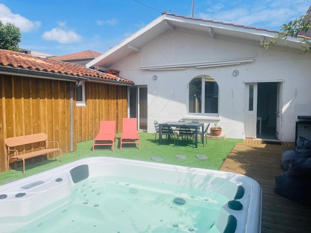 a hot tub in a yard next to a house at Cabane de Pénélope avec spa privé centre-ville et plage in Andernos-les-Bains
