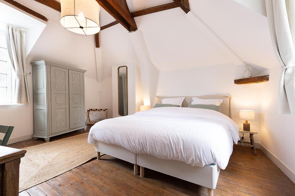a white bedroom with a white bed and a window at Au coeur de Marlotte in Bourron-Marlotte