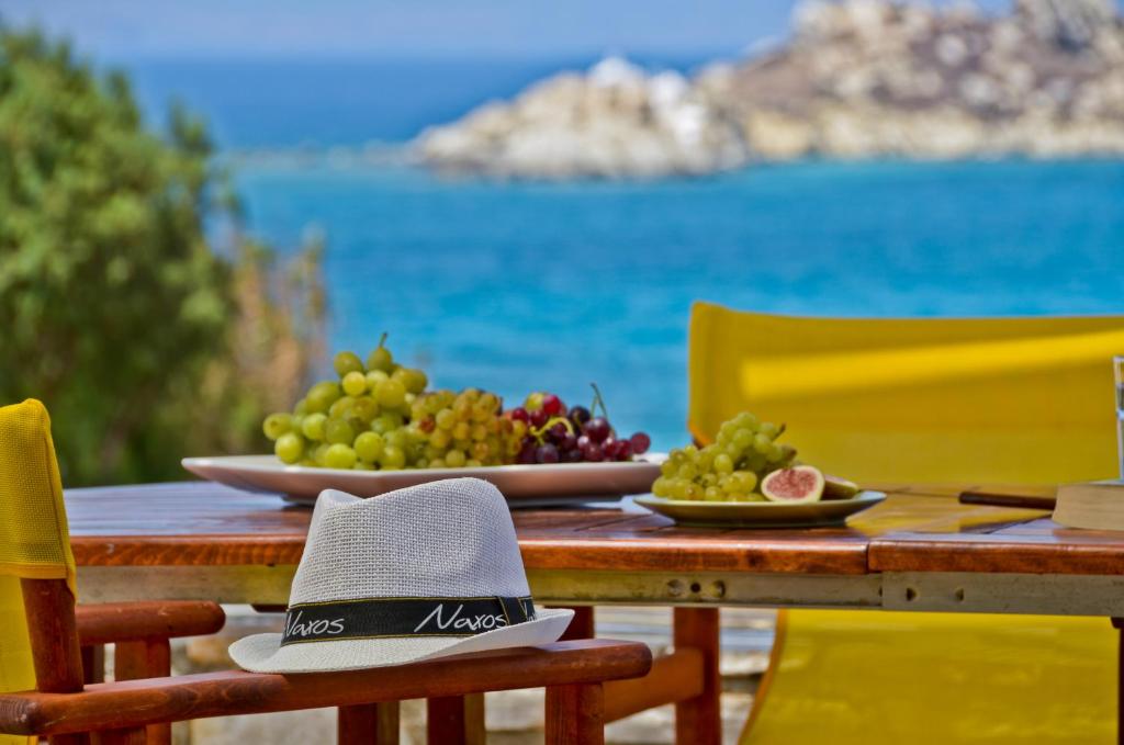 a table with a bowl of fruit and a hat on it at Ydreos Studios & Apartments in Mikri Vigla