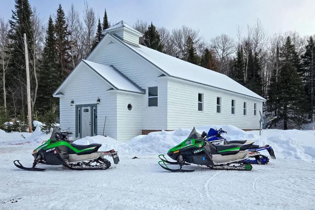 two motorcycles parked in the snow in front of a building at half Mi to Bill Nicholls Trail Renovated Church in Toivola