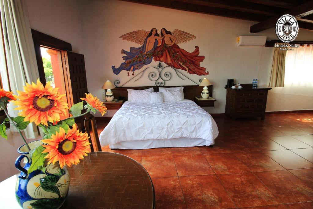 a bedroom with a bed with a painting on the wall at Villa San Jose Hotel & Suites in Morelia