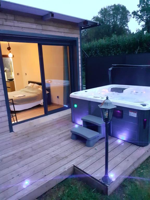 un bain à remous installé sur une terrasse en bois avec une chambre dans l'établissement La Cabane Secrète, à Bouquelon
