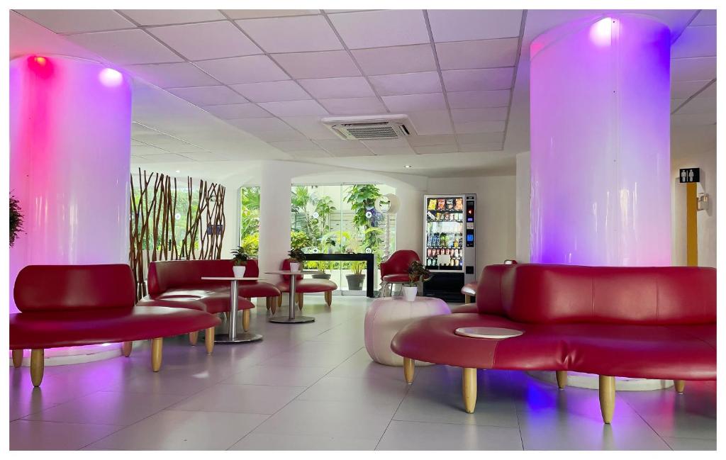 a waiting room with red chairs and purple chairs at Adhara Express in Cancún