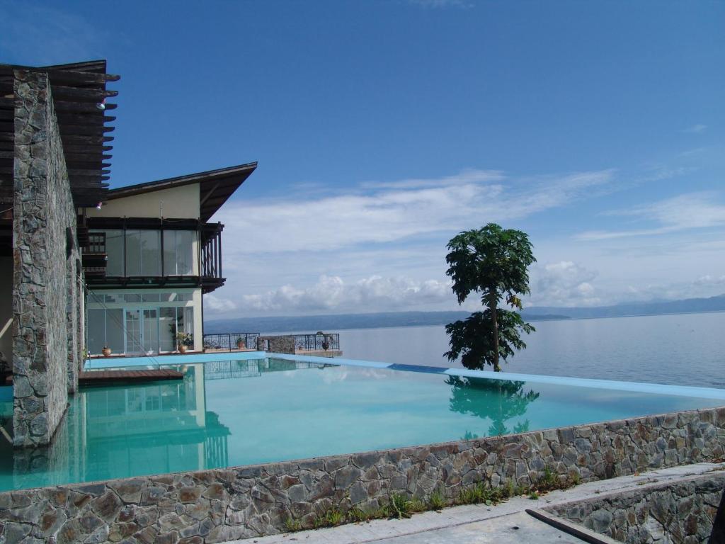 a swimming pool in front of a house next to the water at Tiara Bunga Hotel & Villa in Balige