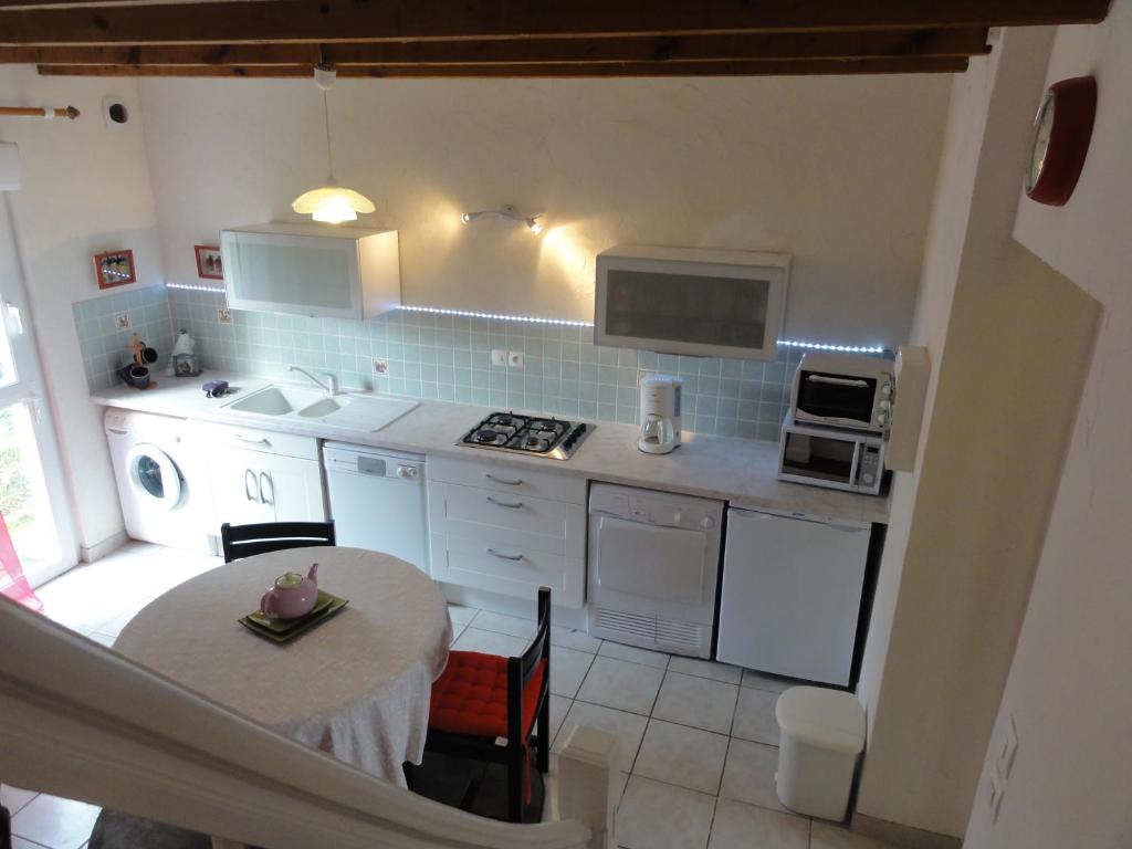a kitchen with a table and a kitchen with white appliances at Gîtes Air Marin in Becléguer