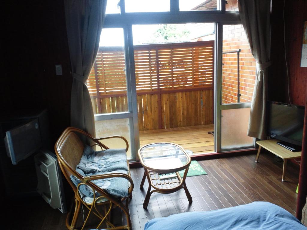 a room with a bed and a chair and a table at Guest House Miyakojima in Miyako-jima