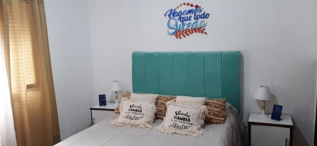 a bedroom with a bed with a green headboard and pillows at La Casita del Mar in Mar del Tuyú